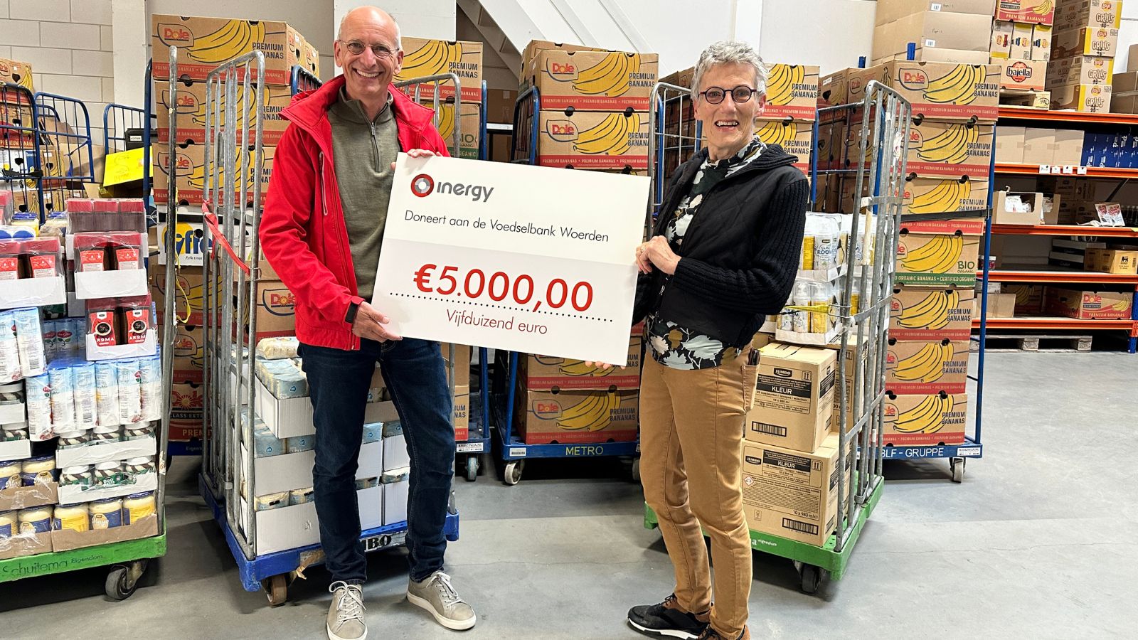 Mathijs overhandigt cheque van 5000 euro aan een vrijwilliger van de voedselbank in Woerden