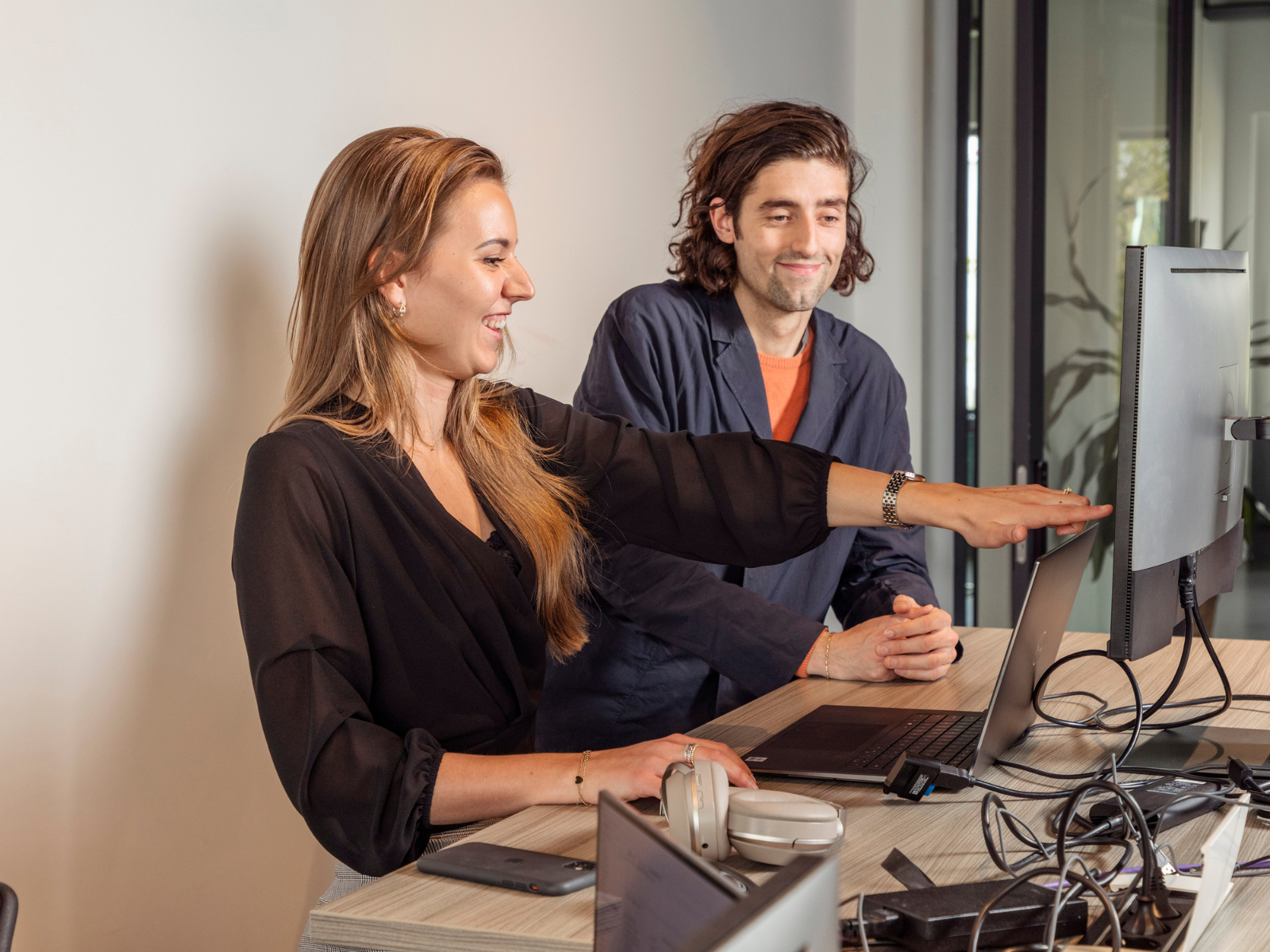 collega's Carmen Verweij en David van der Eng achter een laptop op kantoor in Woerden